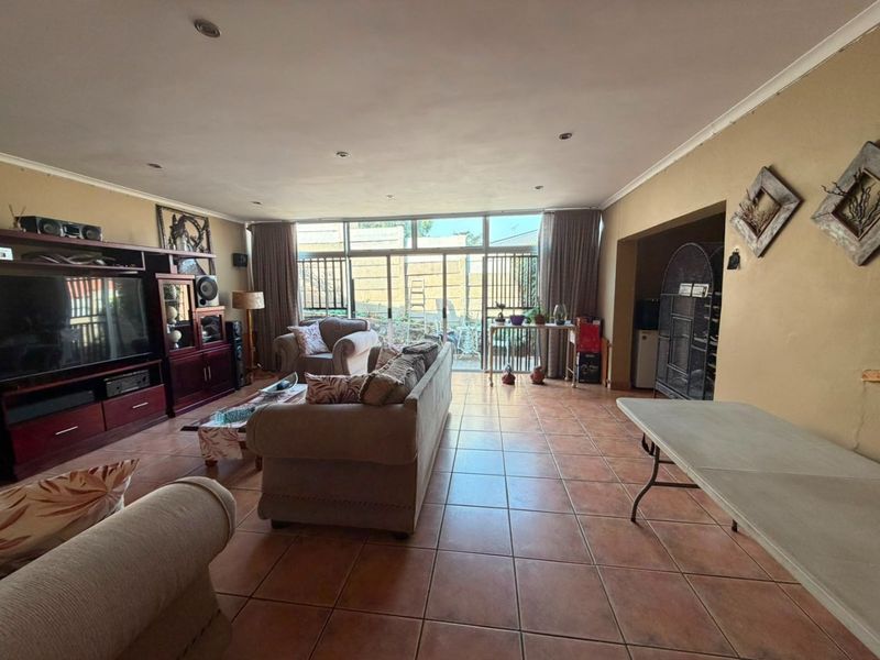 Spacious living room featuring tiled flooring, recessed lighting, and large sliding glass doors that provide ample natural light and access to the rear exterior.