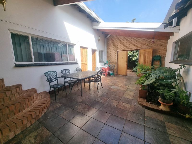A covered outdoor patio area featuring tiled flooring, a brick feature wall, and exposed timber beams, providing a functional space for outdoor living.