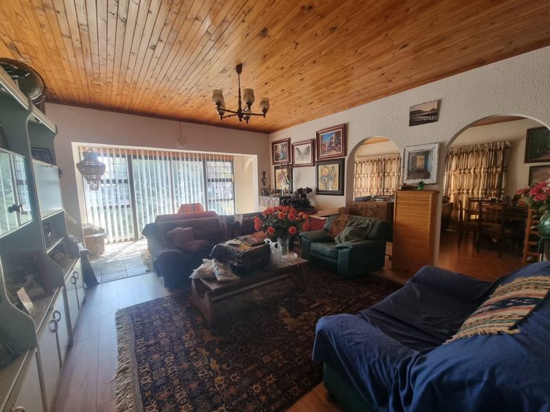 Spacious living room featuring a timber tongue and groove ceiling, arched architectural details, and large sliding glass doors providing access to the outdoor area.