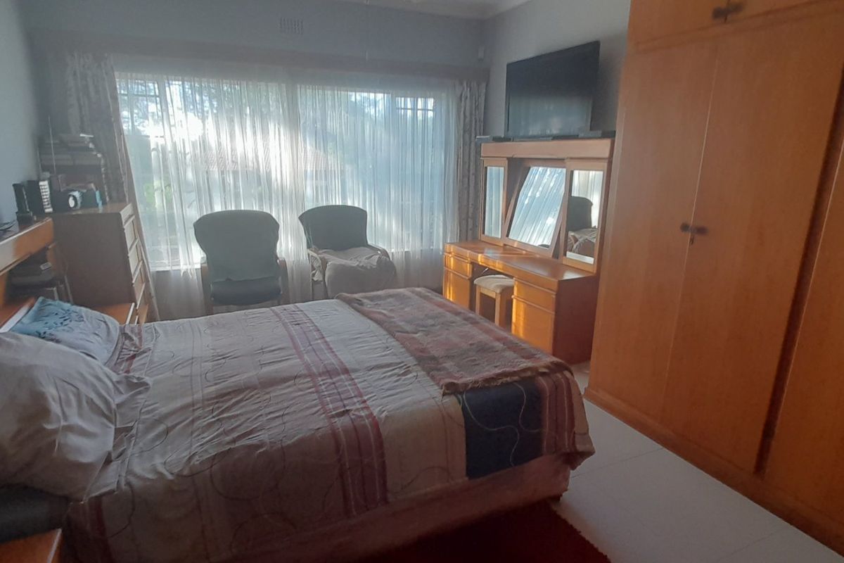 A bedroom featuring built-in wooden cabinetry, tiled flooring, and a large window allowing natural light.