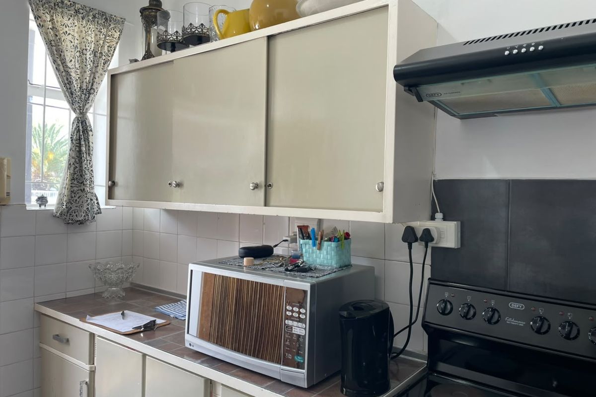 A functional kitchen featuring built-in cabinetry, a tiled backsplash, and a fitted electric stove with an extractor fan.