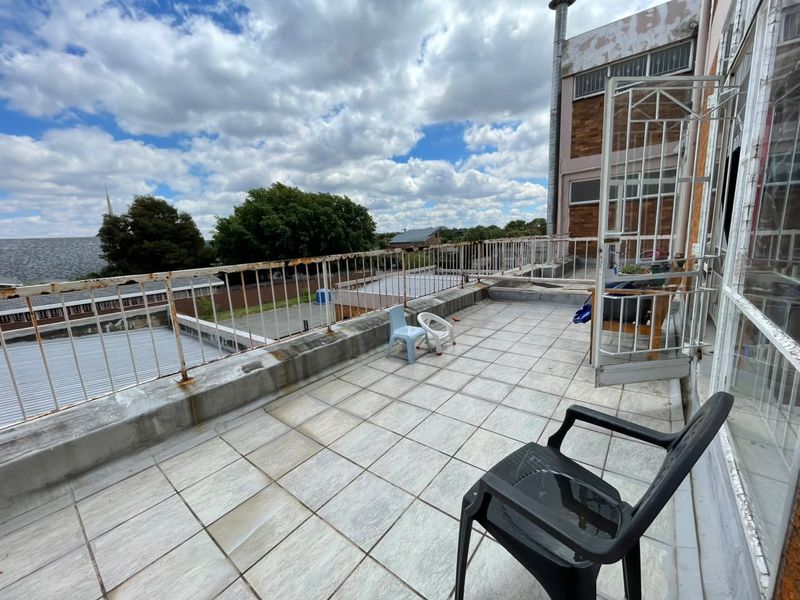 Spacious open balcony featuring tiled flooring and metal balustrades, offering an elevated outdoor area with potential for renovation and aesthetic improvement.