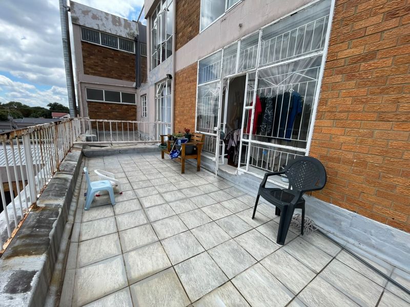 Spacious apartment balcony featuring tiled flooring and metal balustrades, offering an outdoor area with potential for renovation and improved aesthetic appeal.