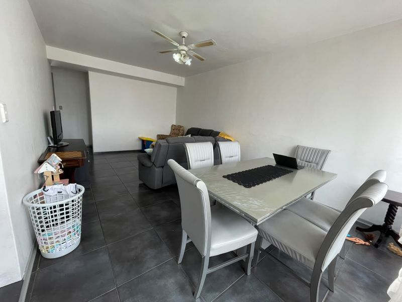 Open plan living and dining area featuring large format floor tiles and a central ceiling fan.