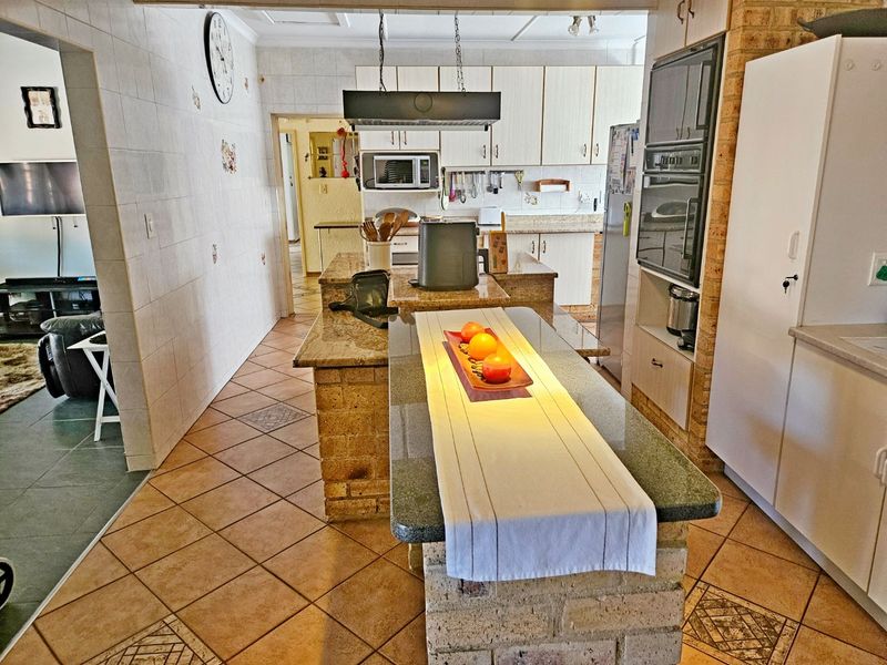 A functional kitchen featuring a central brick island with granite countertops, built-in oven, microwave, and tiled finishes throughout.