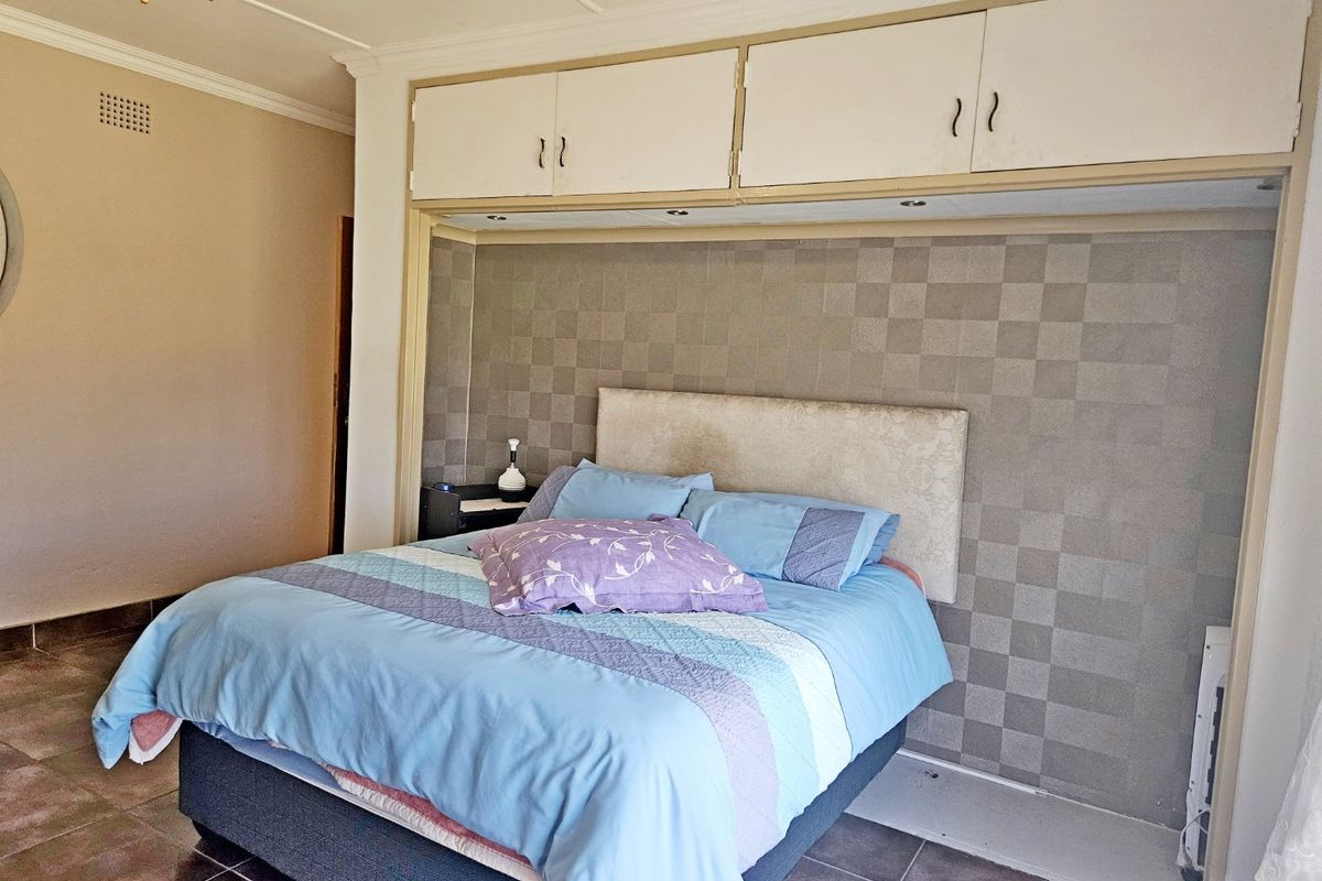 A bedroom featuring built-in overhead cupboards, tiled flooring, and a ceiling fan, providing functional storage and basic finishes.
