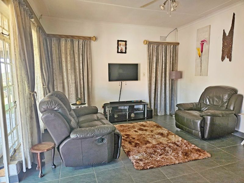A living room featuring tiled flooring, a ceiling fan, and a sliding glass door providing access to the exterior.