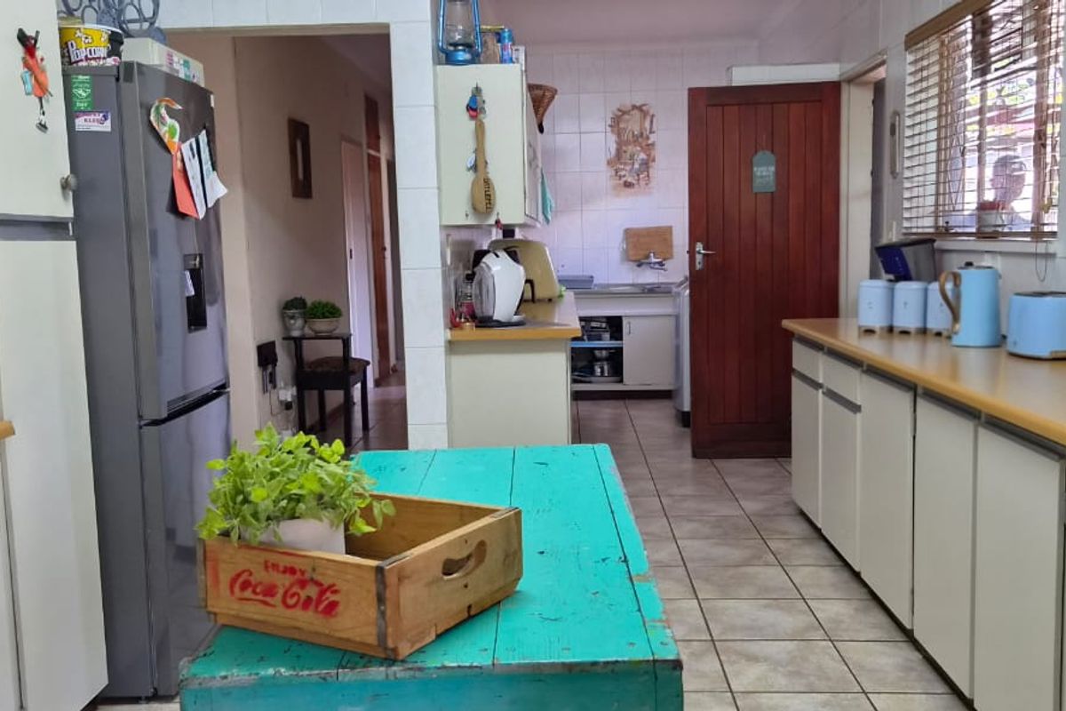 A functional kitchen featuring laminate countertops, tiled flooring, and wall tiling, with built-in cabinetry and a traditional timber door.