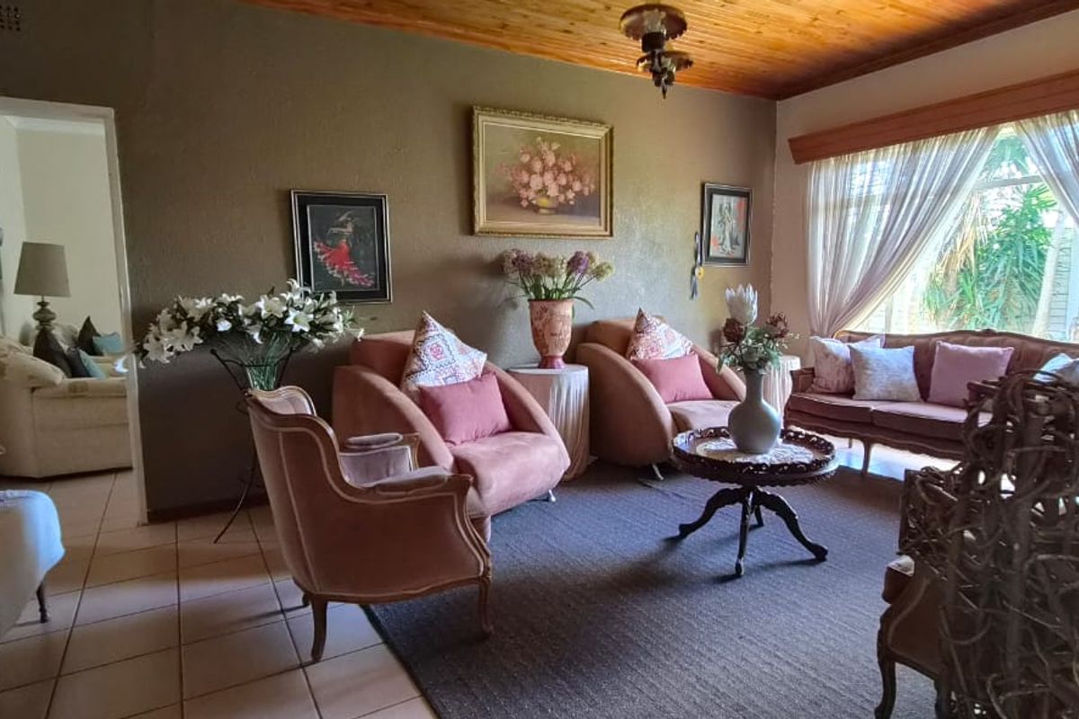 A spacious living room featuring a warm timber ceiling, tiled flooring, and large windows that provide natural light.