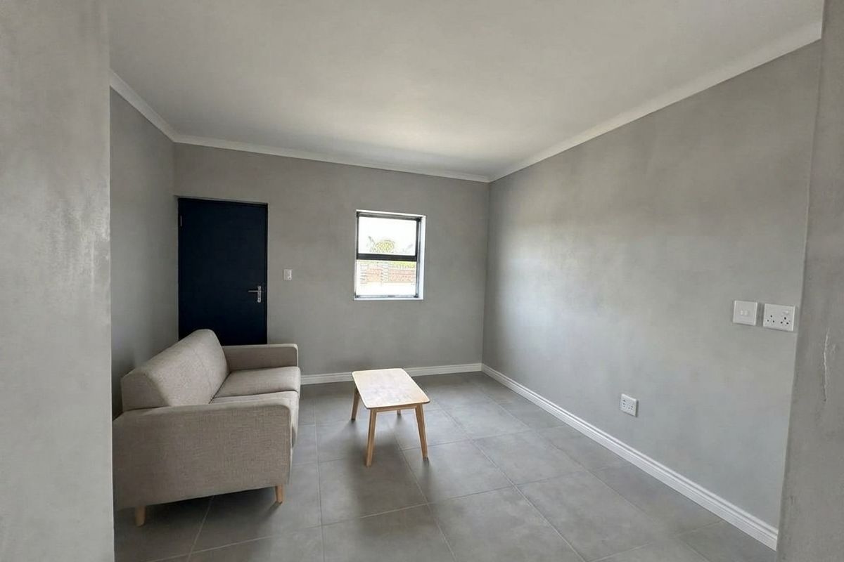 A minimalist living room featuring neutral grey walls, large format floor tiles, and clean white trim finishes.