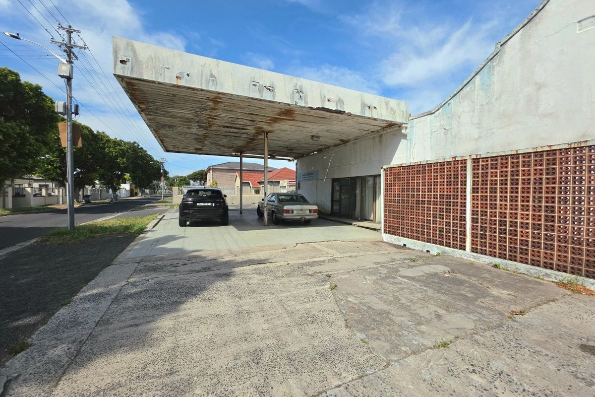 Front exterior view of a commercial property featuring a large concrete canopy, breeze block wall, and a weathered concrete driveway.