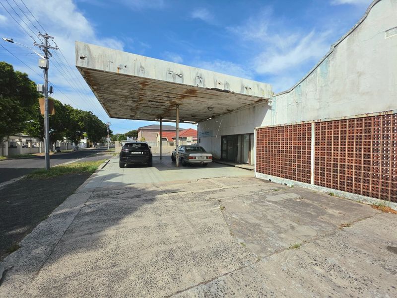 Front exterior view of a commercial property featuring a large concrete canopy, breeze block wall, and a weathered concrete driveway.