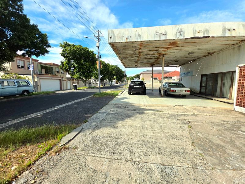 Commercial property frontage featuring a large concrete canopy, paved driveway area, and storefront entrance in a street-facing location.