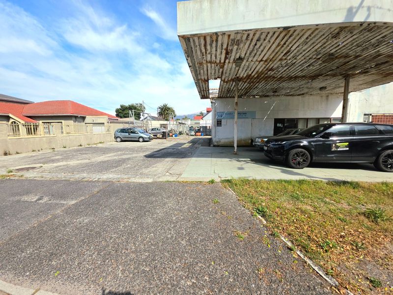 Commercial property exterior featuring a large asphalt parking area and a weathered concrete canopy structure requiring maintenance.