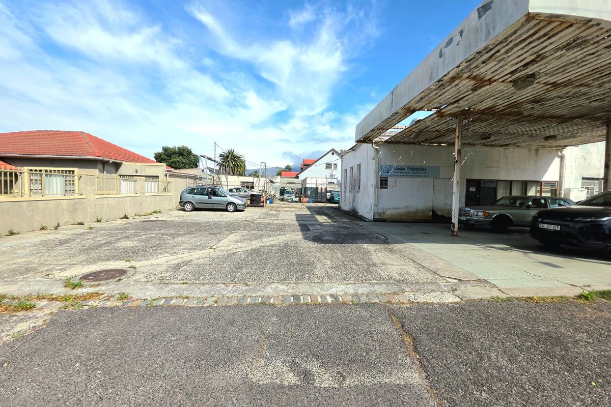Commercial property exterior featuring a large concrete forecourt, a weathered metal canopy, and perimeter boundary walls, suitable for redevelopment or commercial use.
