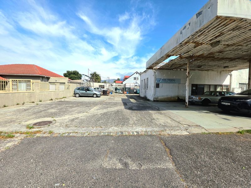 Commercial property exterior featuring a large concrete forecourt, a weathered metal canopy, and perimeter boundary walls, suitable for redevelopment or commercial use.
