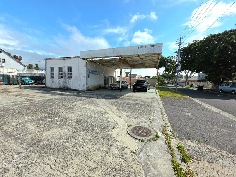 Commercial property featuring a large concrete canopy and paved forecourt area, showing significant signs of weathering and wear on the exterior structure.