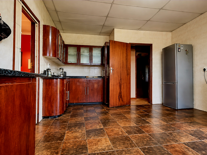 A dated kitchen featuring dark wood cabinetry, tiled flooring, and tiled walls, offering a functional layout with potential for modern renovation.