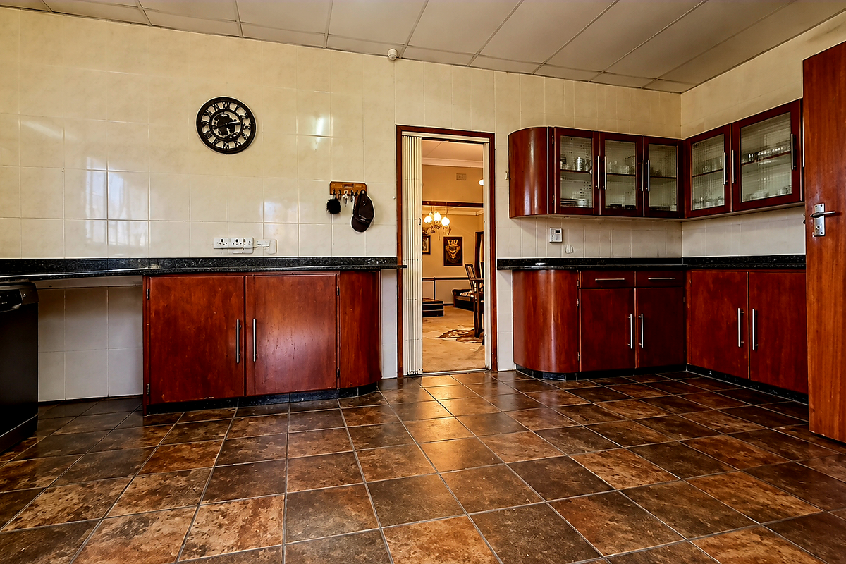 A functional kitchen featuring dark wood cabinetry, tiled splashbacks, and durable floor tiles, offering a practical layout with ample storage space.