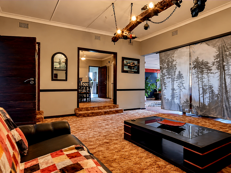 Spacious living room featuring a raised floor level, timber beam ceiling detail, and wall sconces, offering a versatile layout for comfortable family living.