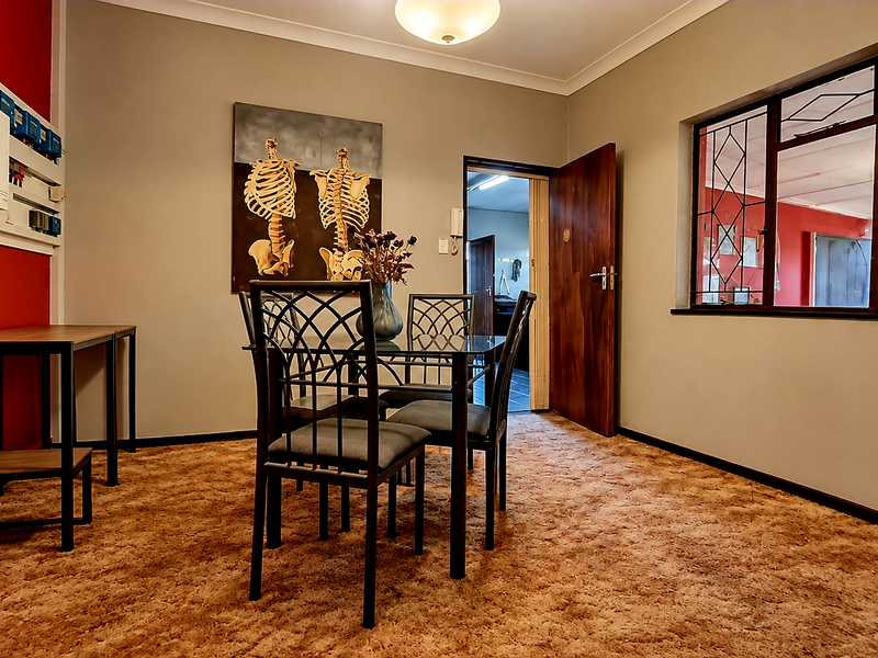 Dining room featuring carpet flooring, security bars on windows, and a wall-mounted solar inverter system.