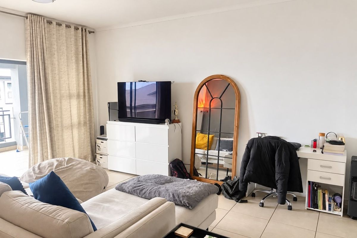A bright living room featuring tiled flooring and a sliding glass door leading to an outdoor balcony area.