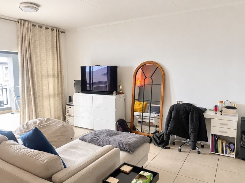A bright living room featuring tiled flooring and a sliding glass door leading to an outdoor balcony area.