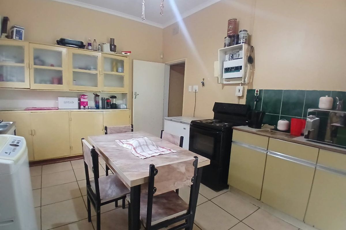 A functional kitchen featuring tiled flooring, built-in cabinetry, and a tiled splashback, offering a dated layout ready for modernization.