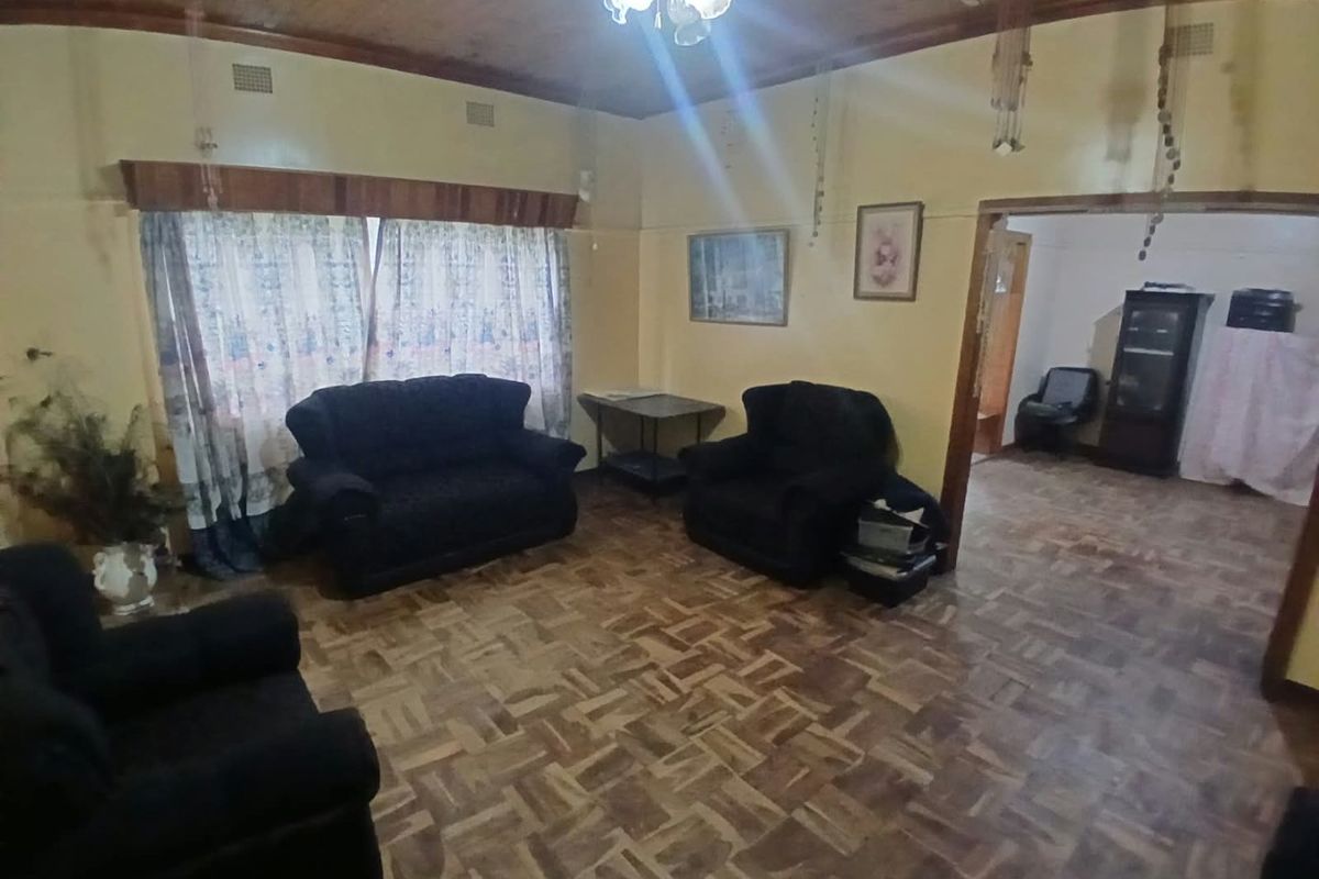 A living room featuring traditional parquet flooring and a timber-paneled ceiling, offering a dated aesthetic with potential for modernization.