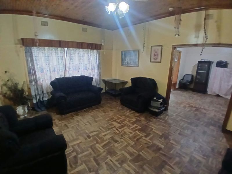 A living room featuring traditional parquet flooring and a timber-paneled ceiling, offering a dated aesthetic with potential for modernization.