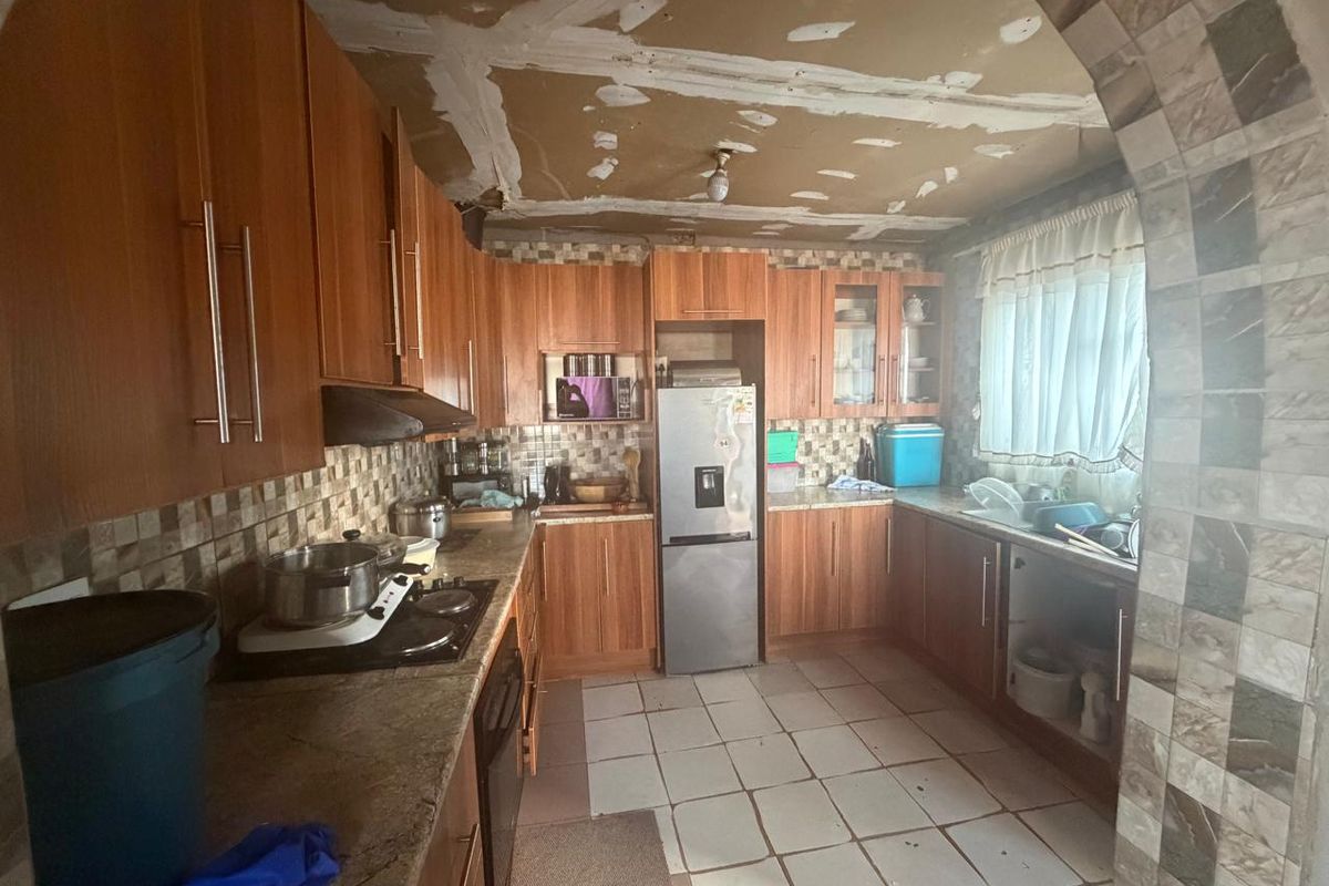 A kitchen featuring wood-look cabinetry and tiled surfaces, currently requiring ceiling repairs and general maintenance to restore its functionality and aesthetic appeal.