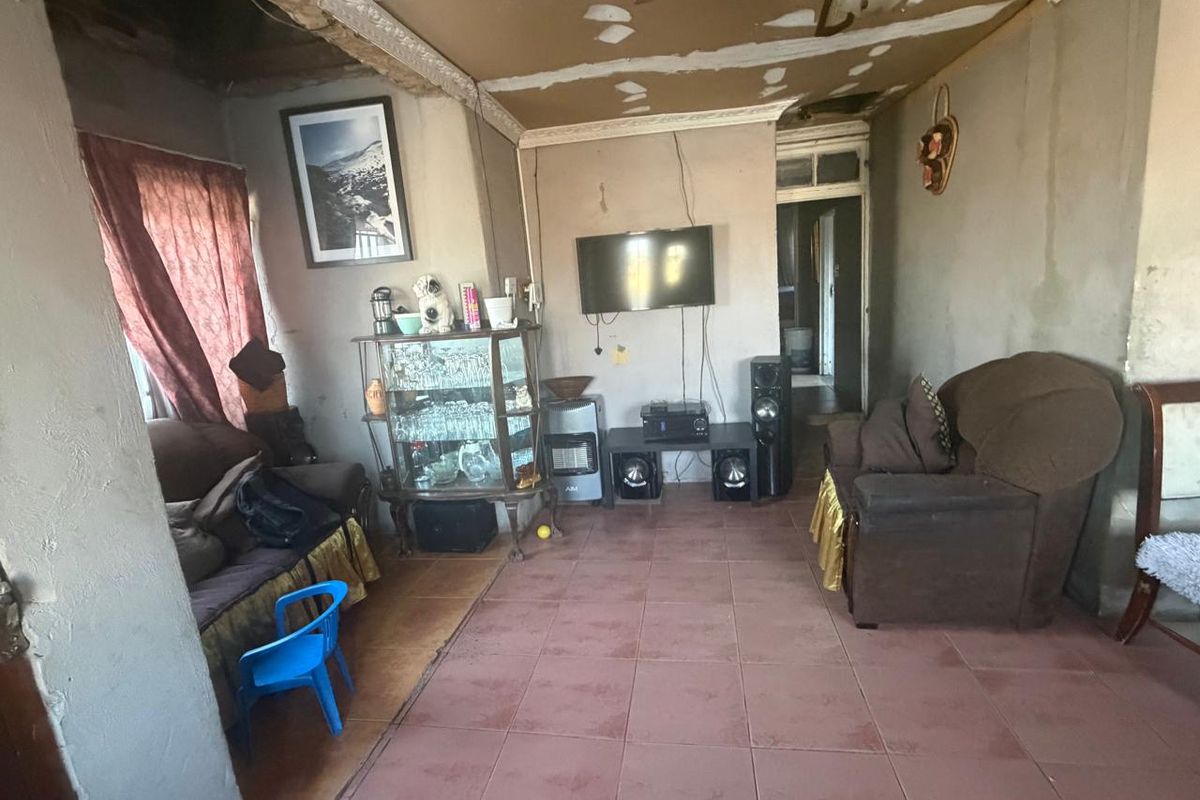 A living room space featuring tiled flooring and coving, currently requiring significant ceiling and wall repairs to improve the overall condition.