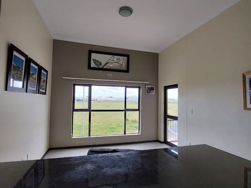 Open plan living area featuring a dark granite kitchen island, neutral walls, and large windows providing natural light and scenic views.