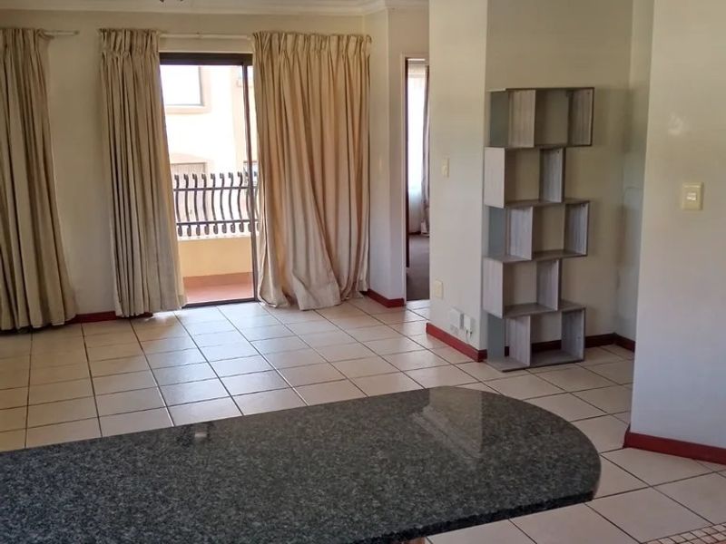 Open plan living area featuring tiled flooring, a granite breakfast bar, and sliding door access to a balcony.