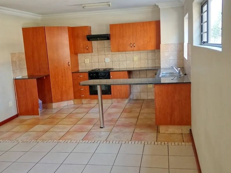 A functional kitchen featuring wooden cabinetry, granite countertops, a breakfast bar, and tiled flooring, offering a clean and practical layout.