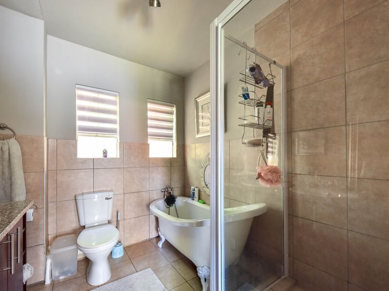 A well-appointed bathroom featuring a classic freestanding bathtub, a separate glass-enclosed shower, and a vanity with granite countertop.