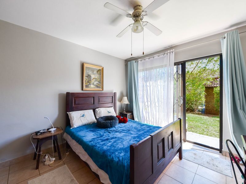 A bedroom featuring tiled flooring, a ceiling fan, and a sliding glass door providing direct access to the garden.