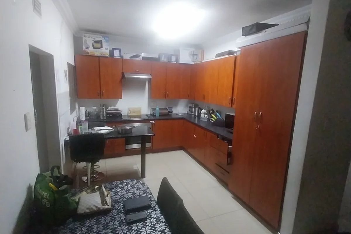 A functional kitchen featuring wooden cabinetry, dark countertops, and built-in appliances, offering a practical layout with tiled flooring throughout.