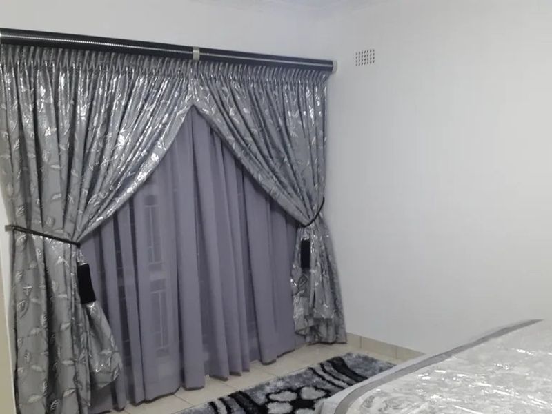 A bedroom featuring tiled flooring, a ventilation grille, and a curtain rail with installed window treatments.