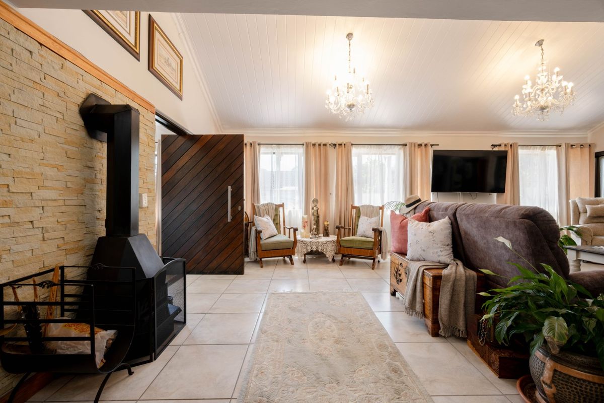 Spacious living room featuring a striking stone-clad fireplace with a wood-burning stove, vaulted ceilings, and elegant tiled flooring throughout.