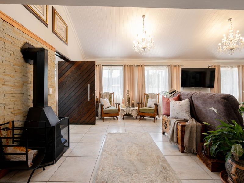 Spacious living room featuring a striking stone-clad fireplace with a wood-burning stove, vaulted ceilings, and elegant tiled flooring throughout.