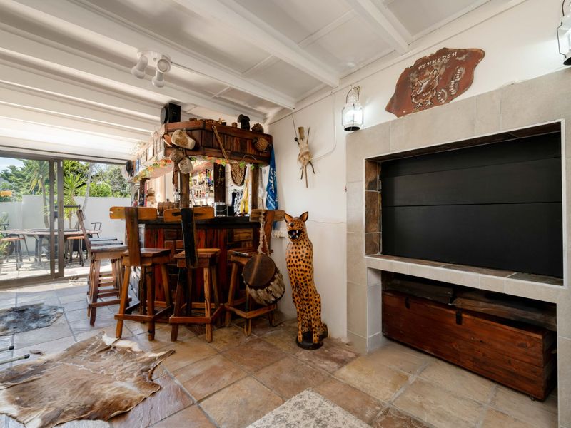 A rustic indoor bar area featuring a built-in bar counter, a large fireplace, tiled flooring, and sliding doors leading to an outdoor patio.