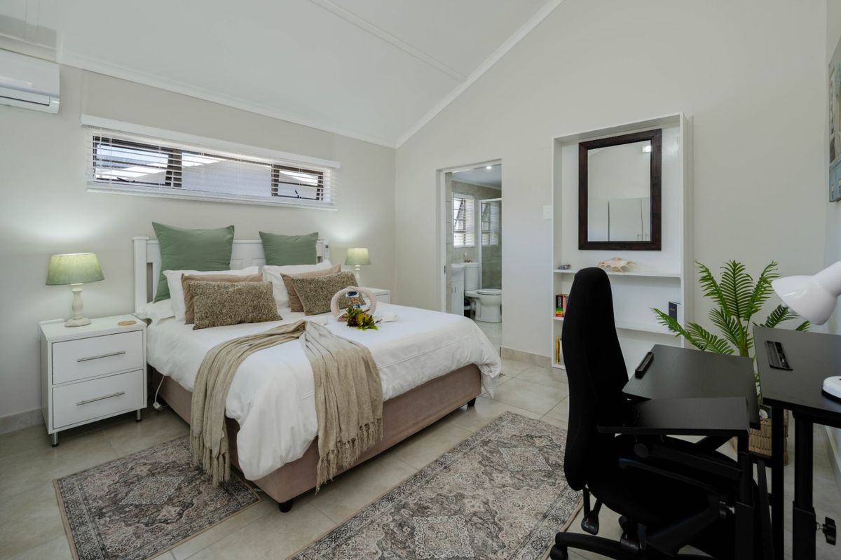 Spacious bedroom featuring a vaulted ceiling, tiled flooring, split-system air conditioning, and convenient en-suite bathroom access.