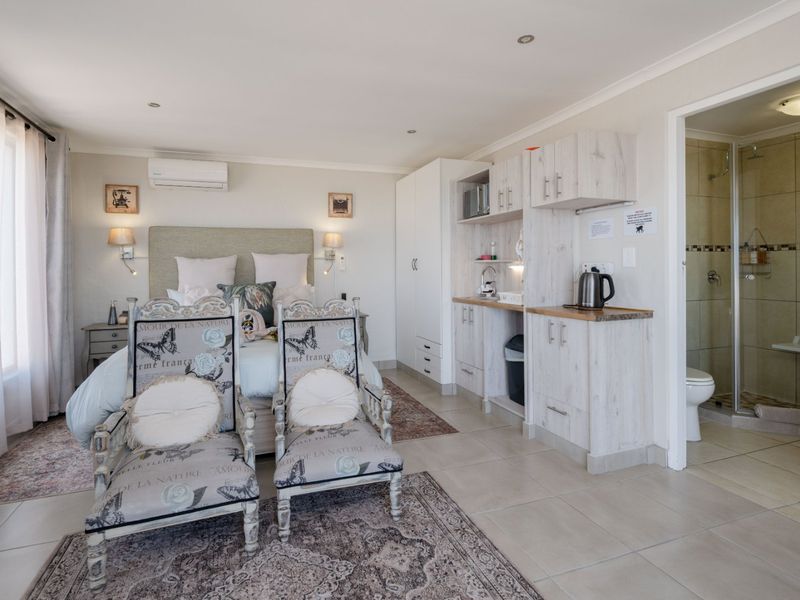 Spacious bedroom featuring tiled flooring, built-in cabinetry, an integrated kitchenette area, and an en-suite bathroom with a shower.