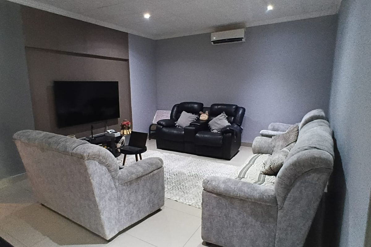A comfortable living room featuring tiled flooring, recessed downlighting, and a wall-mounted split-system air conditioning unit.
