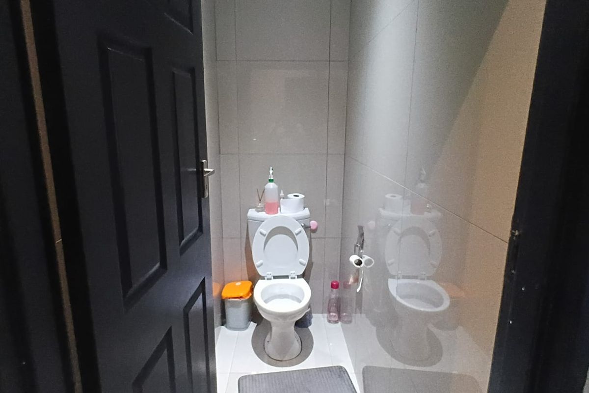A compact bathroom featuring modern tiled walls and flooring with a standard white toilet suite.