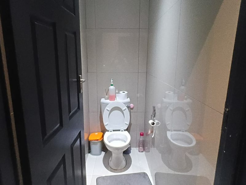 A compact bathroom featuring modern tiled walls and flooring with a standard white toilet suite.