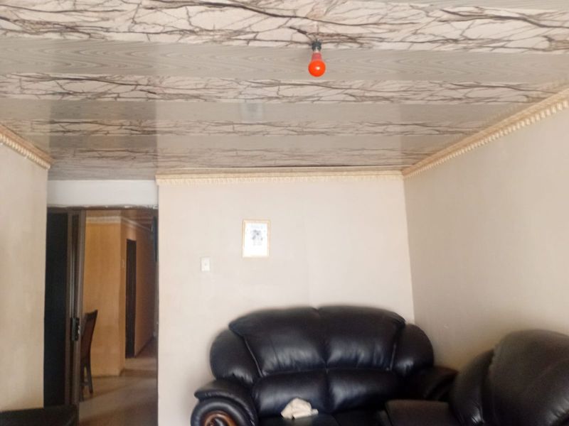 A living room area featuring decorative ceiling molding and a unique patterned ceiling finish, providing a base for potential interior updates.