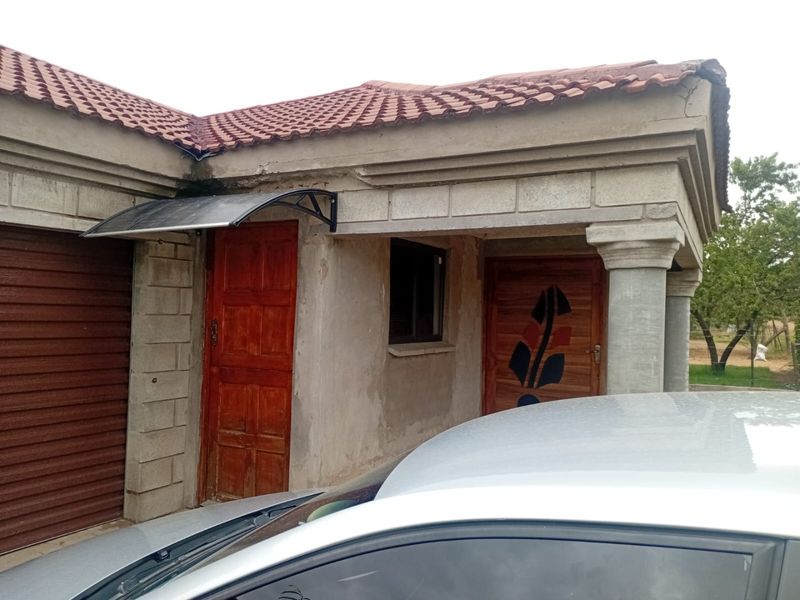 Front exterior view of the property featuring concrete block construction, a tiled roof, and a garage entrance with an installed awning.