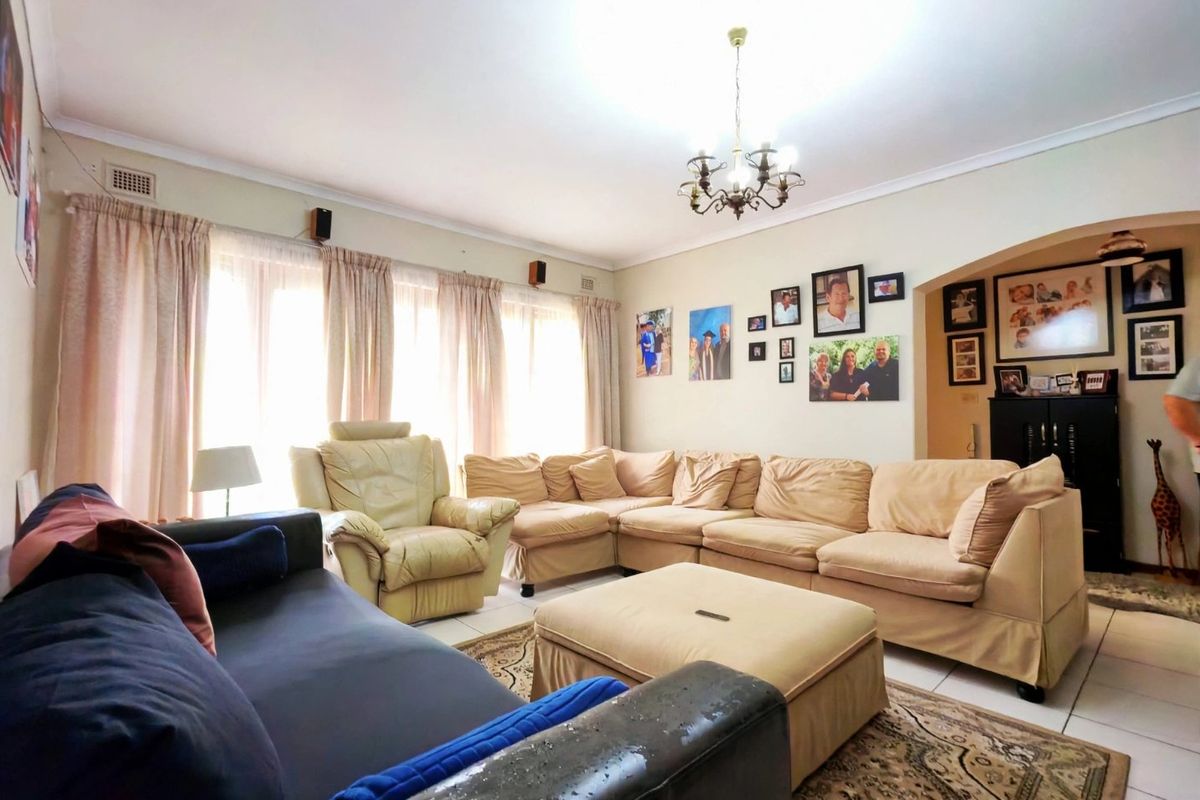 Spacious living room featuring tiled flooring, coved ceilings, and a central chandelier, offering a comfortable and functional layout for relaxation.